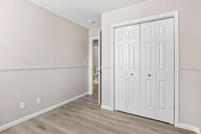 8475 S 1520 W, West Jordan, UT 84088 - unfurnished bedroom with light wood-type flooring, a closet, a textured ceiling, and baseboards