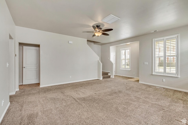 unfurnished room featuring light carpet, stairway, a ceiling fan, and baseboards