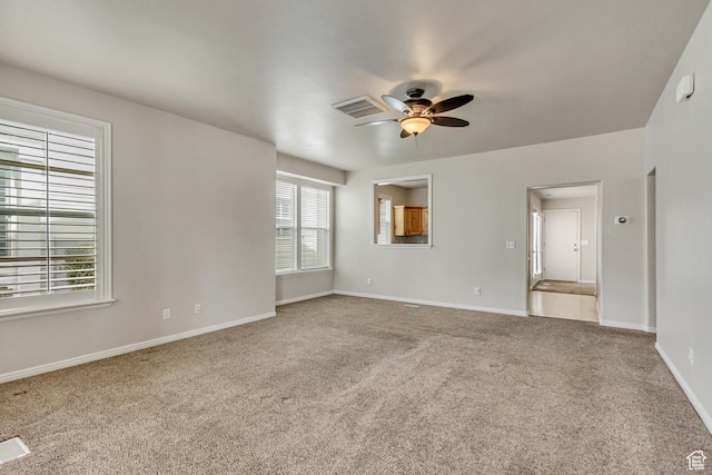 spare room with light colored carpet, ceiling fan, visible vents, and baseboards