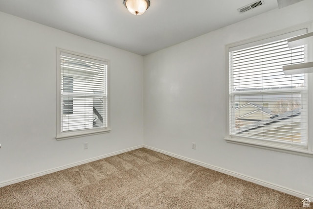 spare room featuring carpet, visible vents, and baseboards