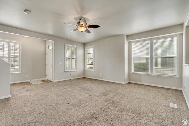 spare room featuring a ceiling fan, a wealth of natural light, and light colored carpet