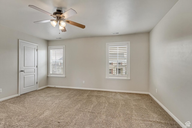 empty room featuring carpet floors, baseboards, visible vents, and a ceiling fan
