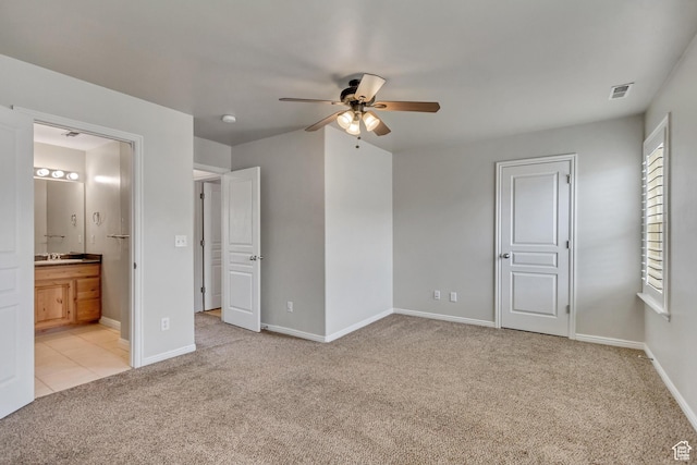 unfurnished bedroom with ensuite bathroom, light carpet, a ceiling fan, visible vents, and baseboards