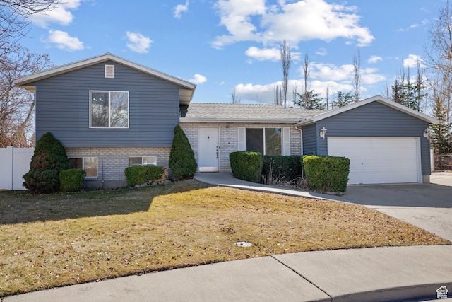 split level home featuring a garage, concrete driveway, brick siding, and a front yard