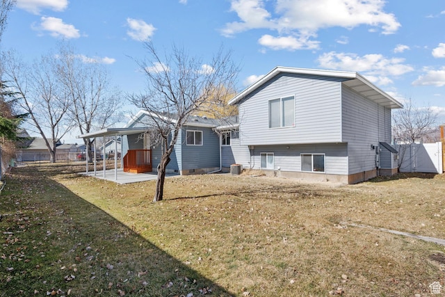 rear view of property featuring a carport, a yard, fence, and central AC unit
