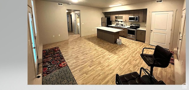 154 E 7th St S Unit A101, Ogden, UT 84404 - kitchen featuring stainless steel appliances, a center island, light wood-style floors, light countertops, and dark brown cabinets