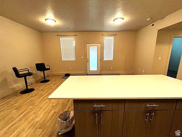 154 E 7th St S Unit A101, Ogden, UT 84404 - kitchen featuring light wood-style flooring, a textured ceiling, baseboards, light countertops, and a kitchen island