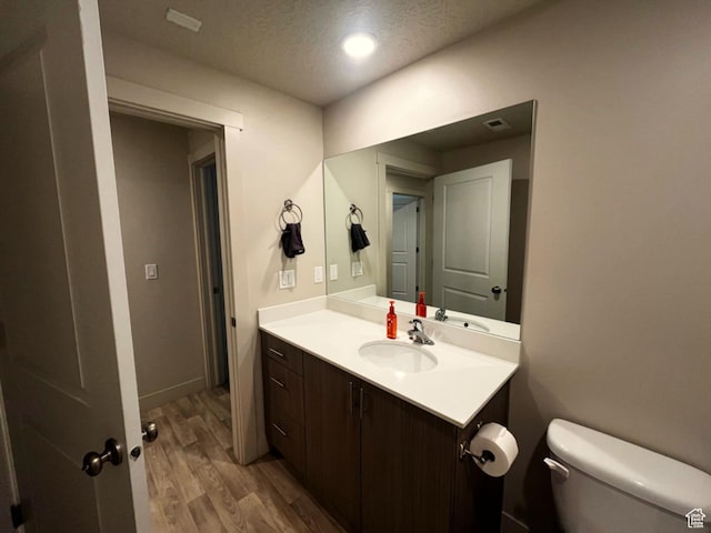 154 E 7th St S Unit A101, Ogden, UT 84404 - half bath with wood finished floors, toilet, vanity, a textured ceiling, and recessed lighting