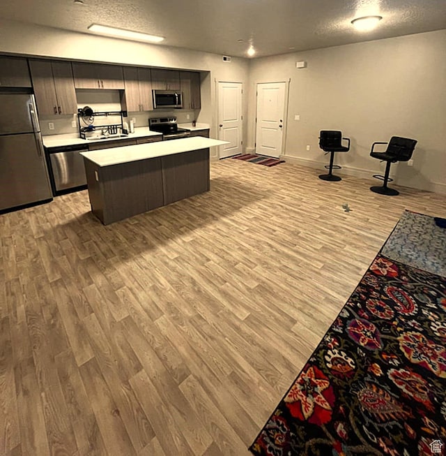 154 E 7th St S Unit A101, Ogden, UT 84404 - kitchen with appliances with stainless steel finishes, light wood-style floors, light countertops, baseboards, and a kitchen island