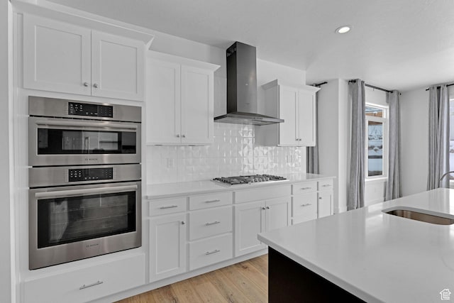 680 E 525 N, Providence, UT 84332 - kitchen featuring light wood-type flooring, wall chimney range hood, light countertops, a sink, and stainless steel appliances
