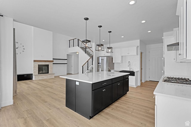 680 E 525 N, Providence, UT 84332 - kitchen featuring white cabinets, light countertops, appliances with stainless steel finishes, dark cabinetry, and a center island with sink