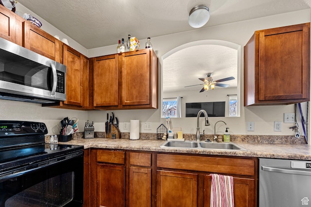 kitchen with appliances with stainless steel finishes, brown cabinetry, light countertops, and a sink
