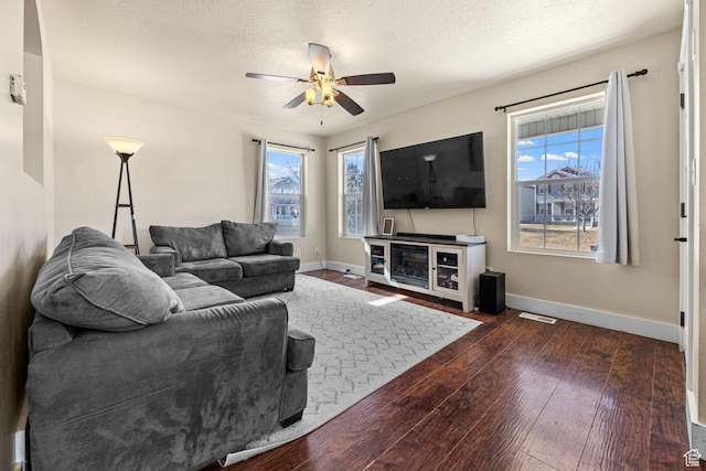 living area featuring plenty of natural light, a textured ceiling, baseboards, and dark wood-type flooring