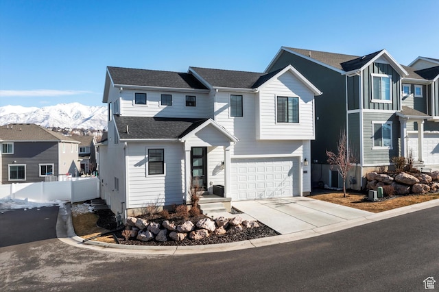 view of front facade with driveway, a garage, a residential view, fence, and a mountain view