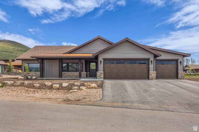 272 Thorn Creek Dr, Kamas, UT 84036 - view of front of home with a garage, driveway, stone siding, and a porch