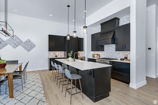 272 Thorn Creek Dr, Kamas, UT 84036 - kitchen featuring dark cabinets, wall chimney range hood, a sink, light countertops, and light wood finished floors