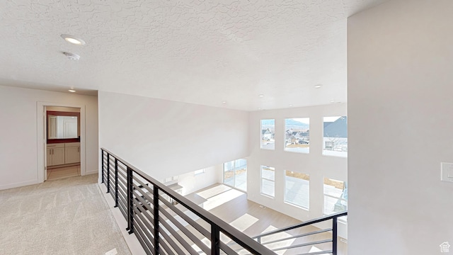 1396 S Castillo Rd W Unit 102, Spanish Fork, UT 84660 - hallway featuring light carpet, baseboards, a textured ceiling, and an upstairs landing