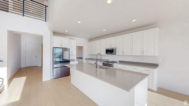 1396 S Castillo Rd W Unit 102, Spanish Fork, UT 84660 - kitchen featuring light wood finished floors, stainless steel appliances, light countertops, a kitchen island with sink, and white cabinetry