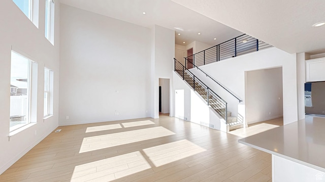 1396 S Castillo Rd W Unit 102, Spanish Fork, UT 84660 - unfurnished living room with a towering ceiling, recessed lighting, stairway, and light wood finished floors