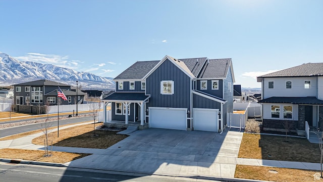view of front of property with concrete driveway, board and batten siding, a mountain view, fence, and a garage
