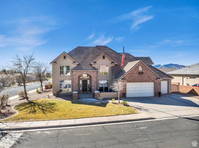 view of front facade with an attached garage, a mountain view, driveway, stucco siding, and a front yard