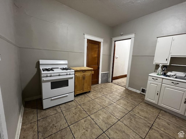 kitchen featuring visible vents, light countertops, white gas range oven, and white cabinetry
