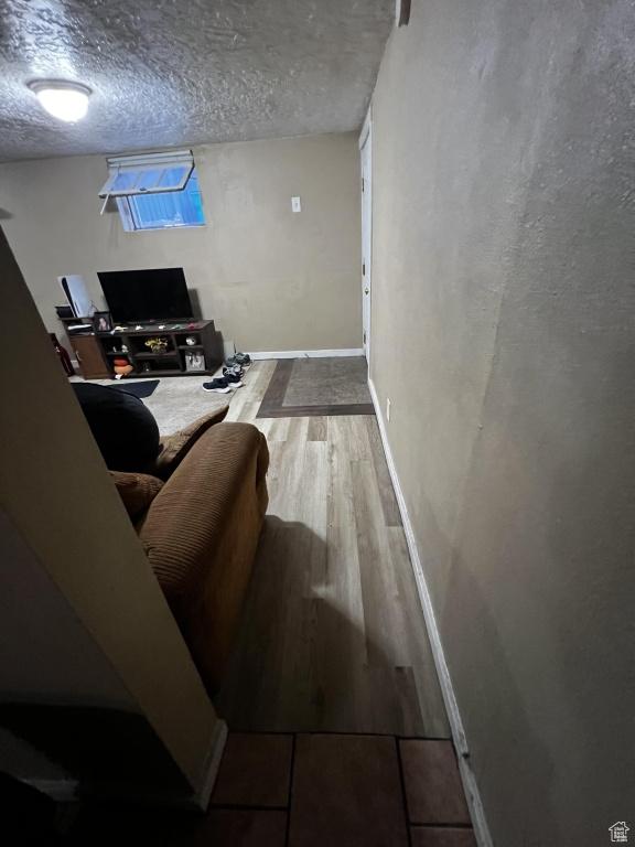 living room featuring a textured ceiling, baseboards, and wood finished floors