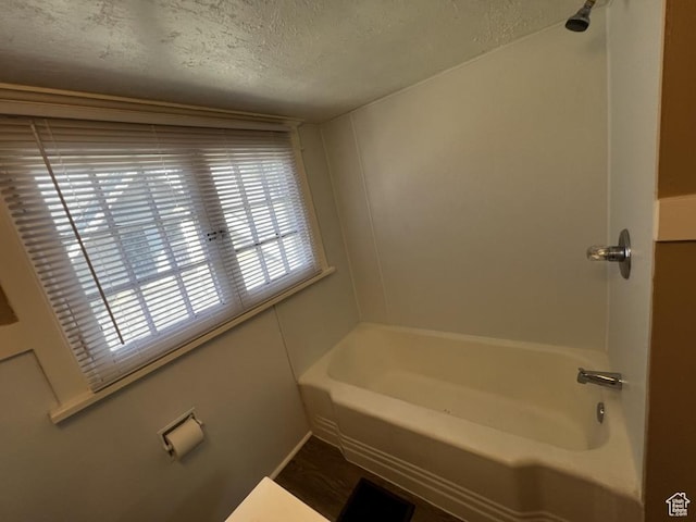 full bath featuring a tub and a textured ceiling