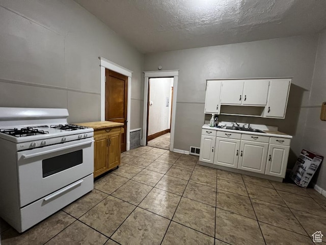 kitchen featuring visible vents, white cabinets, white gas range, light countertops, and a sink