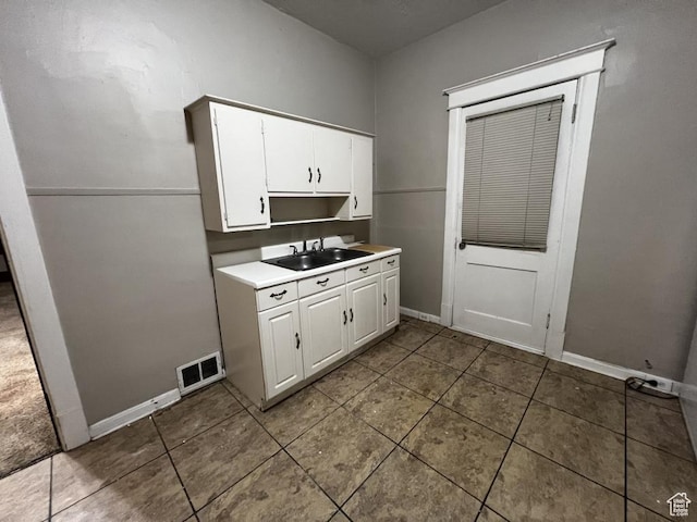 kitchen with tile patterned flooring, a sink, visible vents, white cabinetry, and light countertops