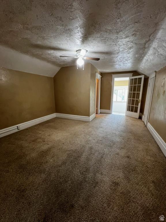 bonus room featuring carpet floors, lofted ceiling, and a textured ceiling