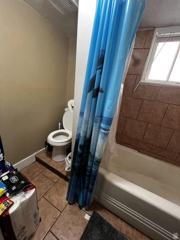 bathroom with a textured ceiling, toilet, baseboards, tile patterned floors, and shower / bath combination with curtain