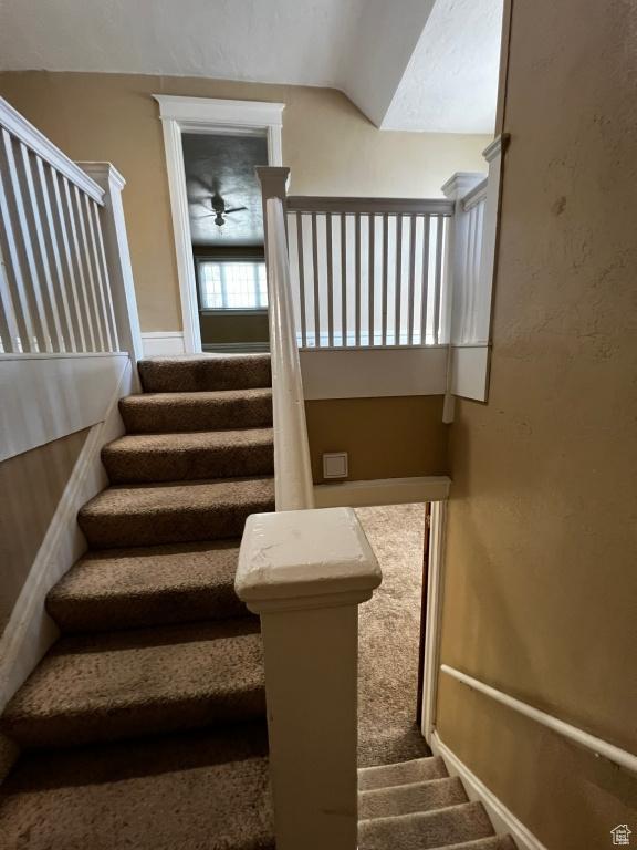 stairway with carpet and vaulted ceiling