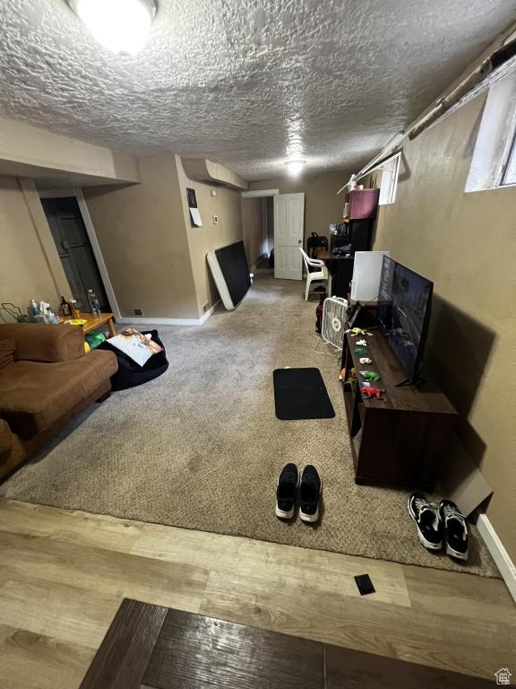 interior space with carpet, baseboards, a textured ceiling, and wood finished floors