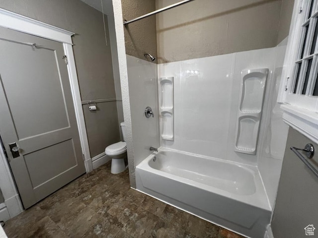 bathroom featuring a textured wall,  shower combination, and toilet
