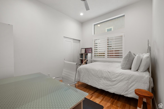 bedroom with wood finished floors, recessed lighting, a closet, ceiling fan, and a high ceiling