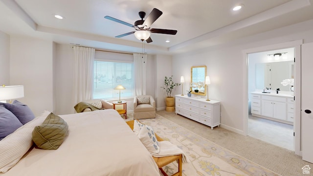 bedroom with light carpet, baseboards, ensuite bathroom, a tray ceiling, and recessed lighting