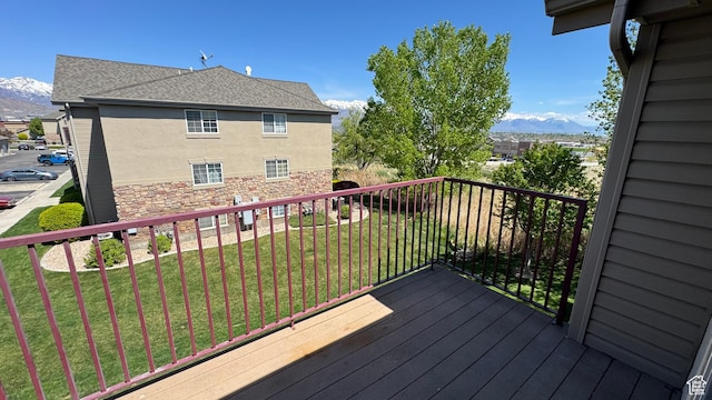 wooden terrace featuring a mountain view and a lawn
