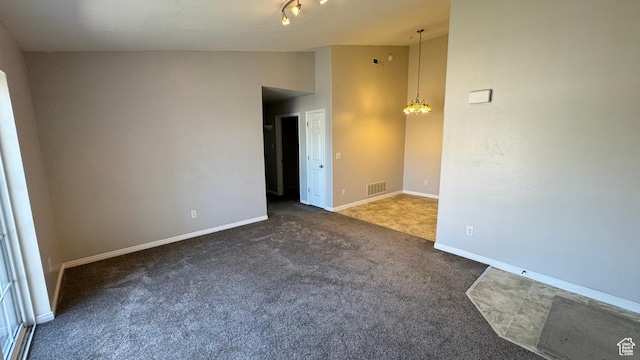 carpeted spare room featuring vaulted ceiling and baseboards