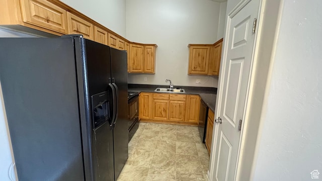 kitchen with black appliances, dark countertops, a sink, and brown cabinets