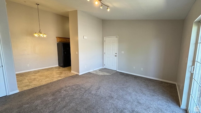 spare room with a chandelier, carpet flooring, baseboards, and lofted ceiling