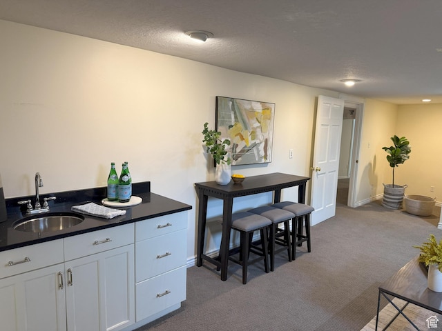 interior space with baseboards, a sink, white cabinetry, dark carpet, and dark countertops