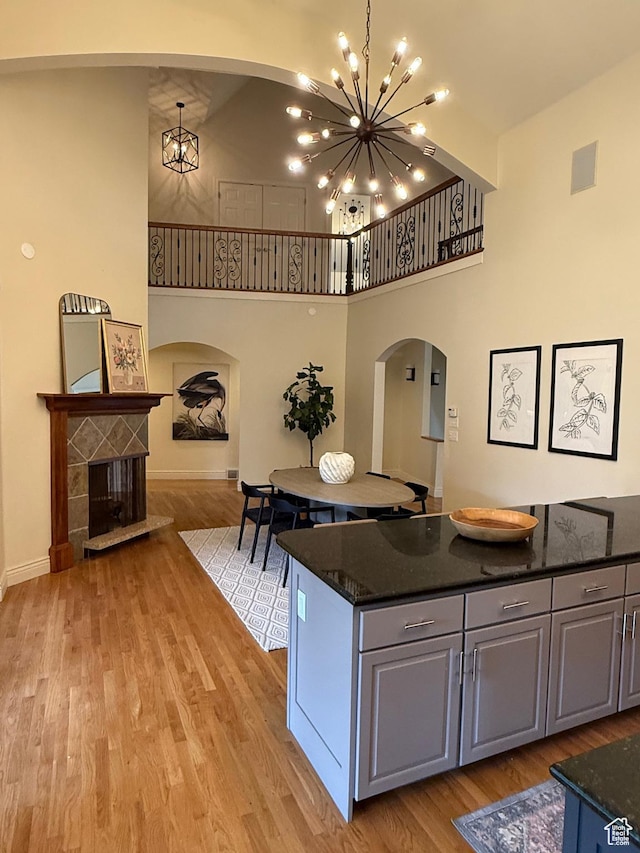 kitchen featuring a chandelier, light wood-style flooring, a high ceiling, and arched walkways