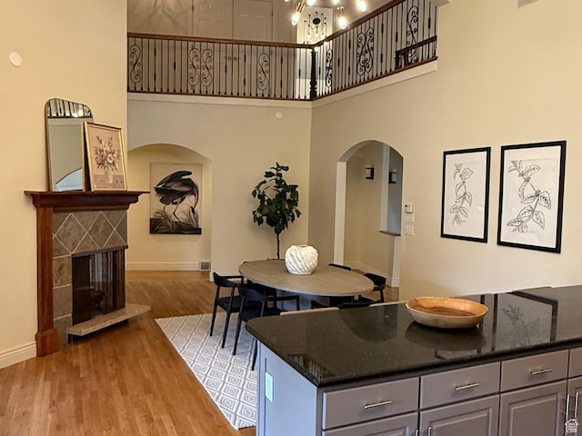 2765 E Blue Spruce Dr, Holladay, UT 84117 - kitchen featuring arched walkways, gray cabinets, baseboards, light wood-style floors, and a towering ceiling