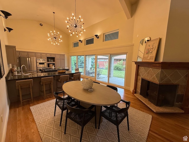2765 E Blue Spruce Dr, Holladay, UT 84117 - dining space featuring a chandelier, a tiled fireplace, wood finished floors, and high vaulted ceiling