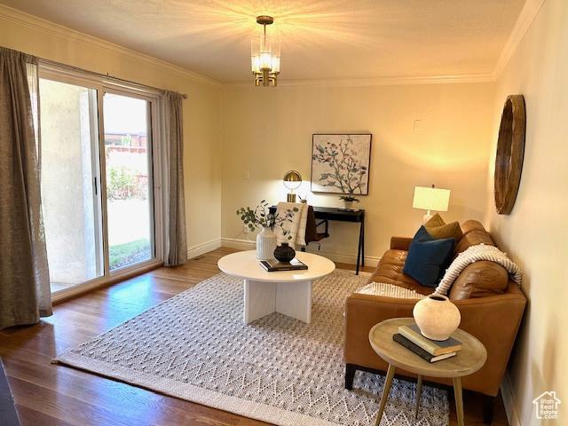 sitting room with baseboards, ornamental molding, a chandelier, and wood finished floors