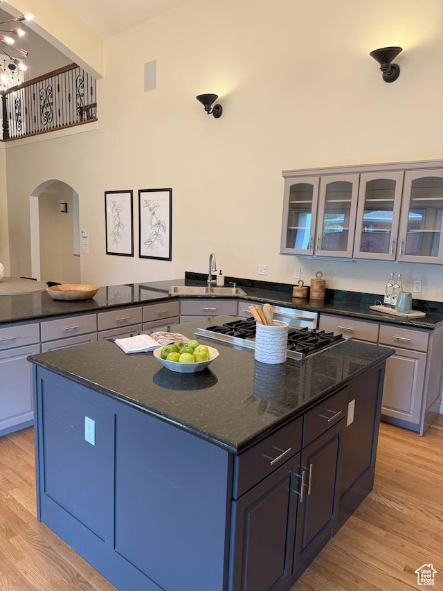 kitchen featuring light wood finished floors, stainless steel gas stovetop, a kitchen island, and arched walkways