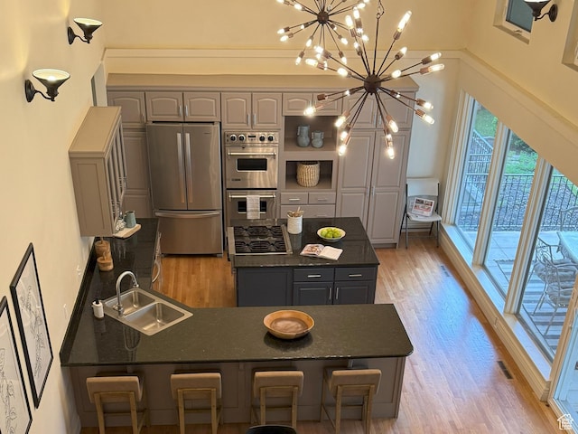 kitchen featuring a sink, dark countertops, stainless steel appliances, light wood-type flooring, and gray cabinetry
