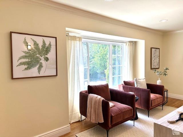sitting room featuring baseboards, light wood-style flooring, and ornamental molding
