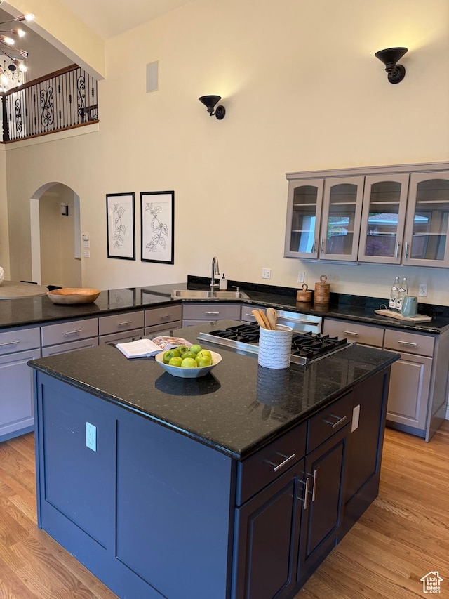 kitchen with a kitchen island, light wood finished floors, stainless steel gas stovetop, and arched walkways